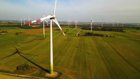 Toma-De-Drones-De-Las-Turbinas-Eólicas-Que-Funcionan-En-Un-Parque-Eólico-Que-Genera-Energía-Eléctrica-Verde-En-Un-Amplio-Campo-Verde-En-Un-Día-Soleado,-Uso-De-Recursos-Renovables-De-Energía,-Deslícese-Hacia-La-Derecha