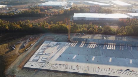 a drone shot of a heavy crane on a construction site with the morning sun and lens flares