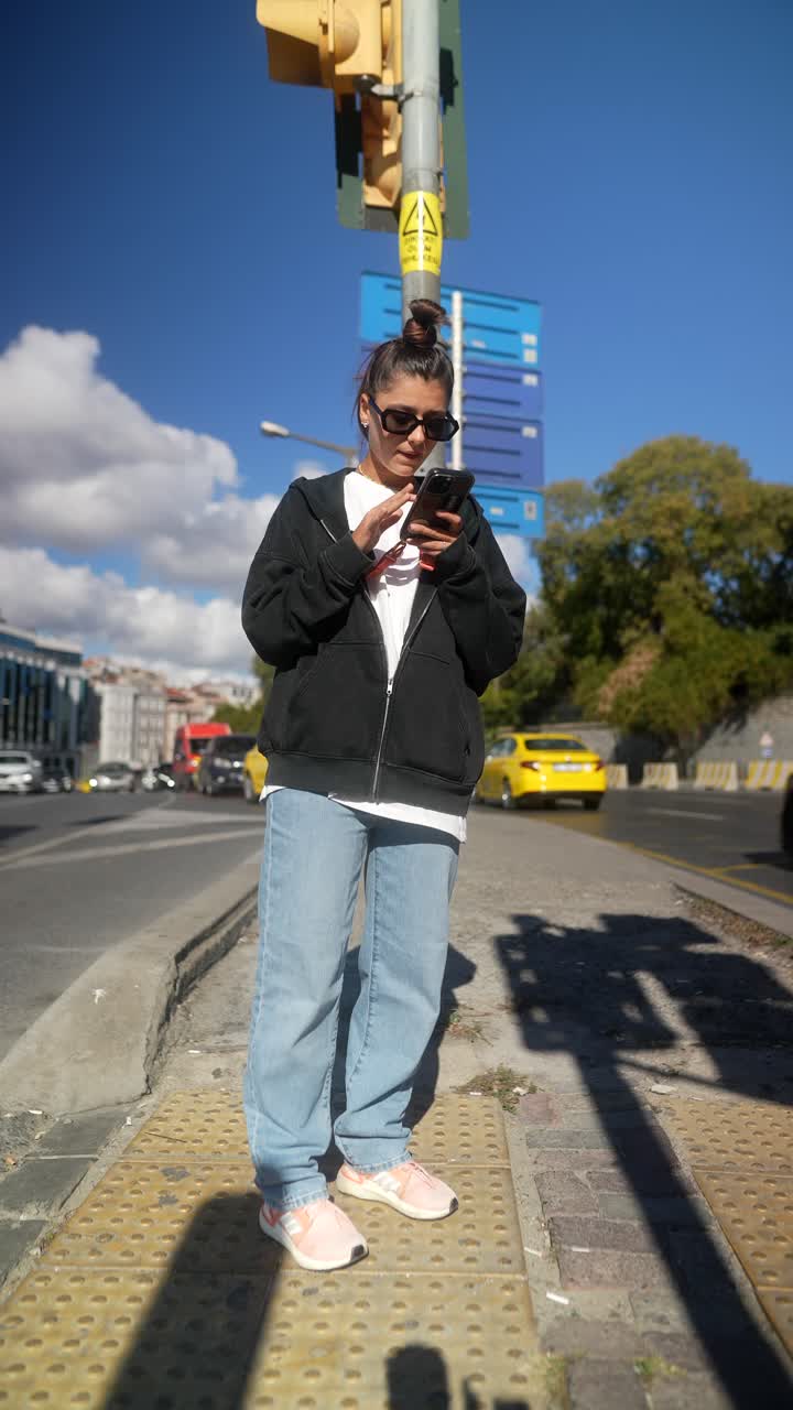 kvinne som bruker telefon ved fotgjengerovergang