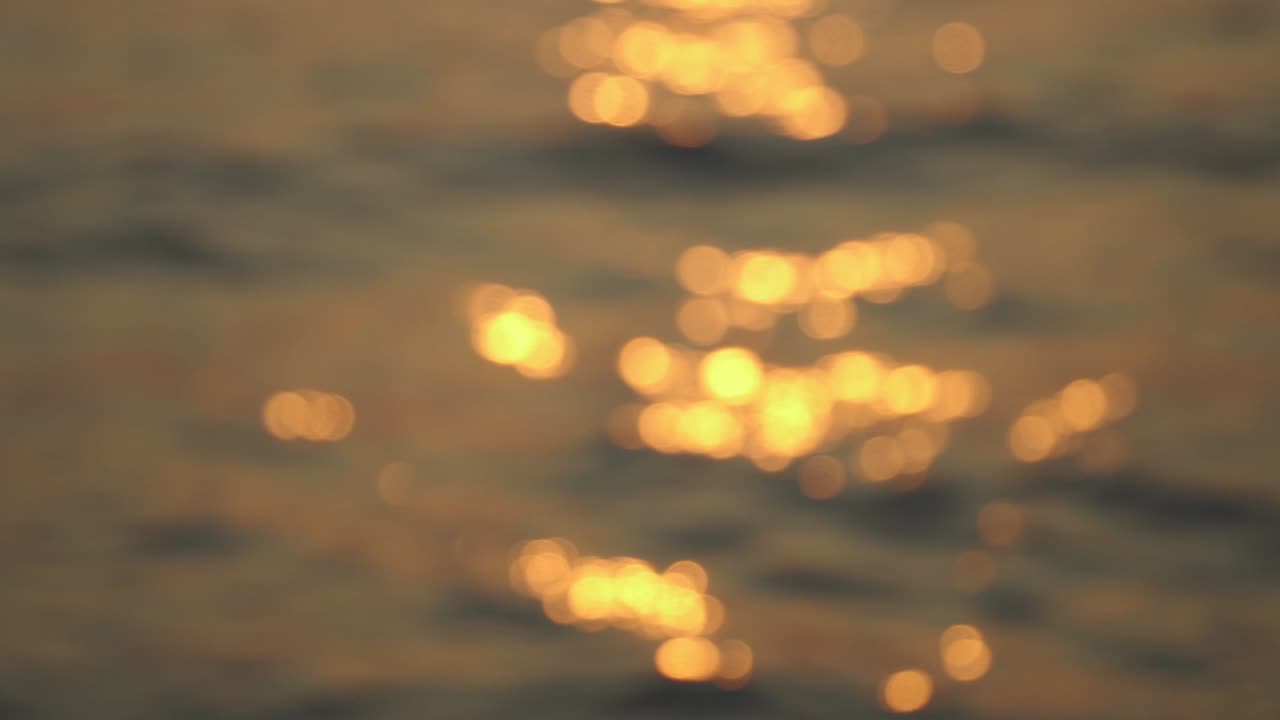 círculos bokeh creados por la luz solar que se refleja en la superficie del mar, grabando video portátil.