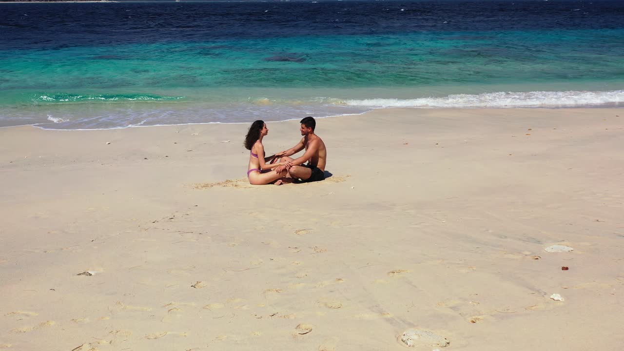 Una giovane coppia innamorata seduta che si gode il sole su un'esotica isola paradisiaca con spiaggia