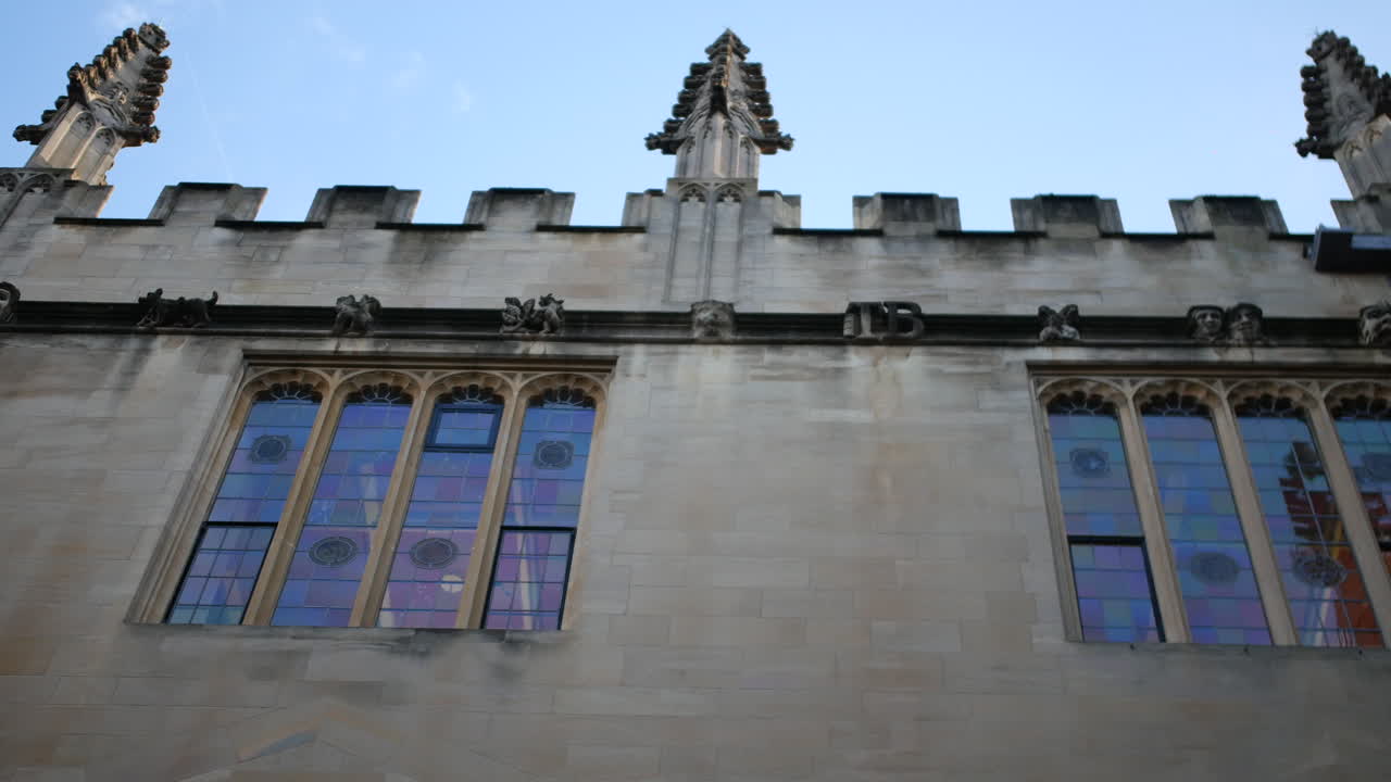 Un'inquadratura dal basso cattura l'ornata architettura gotica di un edificio universitario storico con vetrate colorate che riflettono colori vivaci, ideale per progetti a tema educativo, turistico e patrimoniale