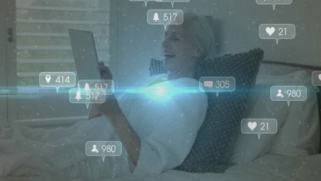using tablet in bed, elderly woman viewing animation of social media notifications