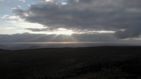 desde el pico de una montaña, el sol rompe a través de las nubes, una interacción divina de luz y sombra sobre el terreno accidentado, exhibido en 4k