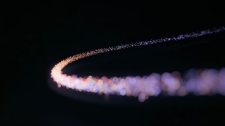 Emitting emitter sending particles along curved arc from lower-left on black void, creating bokeh