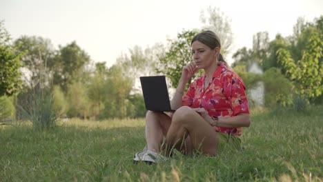 a female freelancer is working on a project using her laptop in a public park.