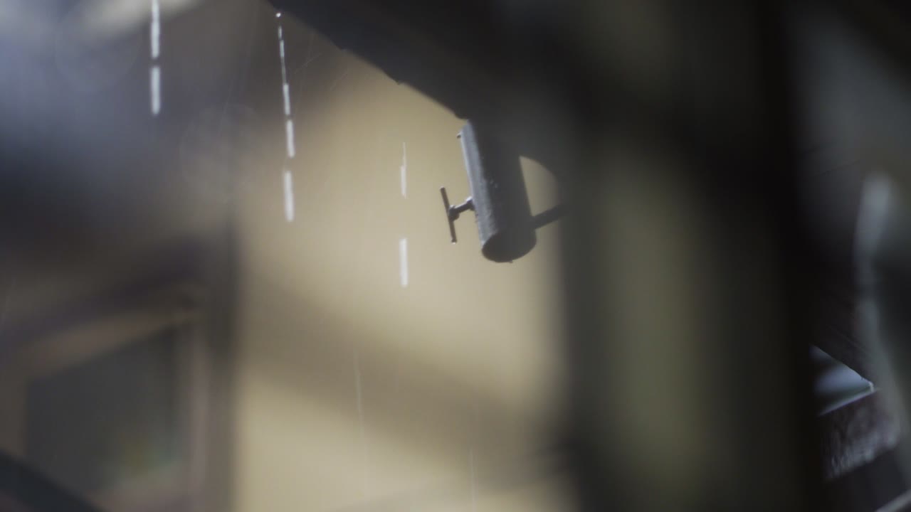 초점이 맞지 않는 배경 건물이 있는 갈색 지붕에서 내리는 가벼운 비