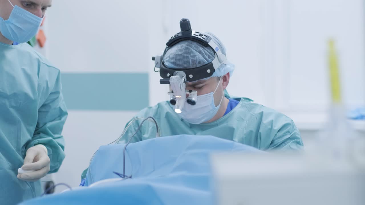 심한 마취 하에서 질을 제거하는 수술, 외과 의사는 최신 장비를 사용합니다, 차가운 플라즈마 방법, 목구에서 부종을 절단합니다, 의사는 새로운 탐지기, 의료 헤드 램프, 수술 루프를 사용합니다.