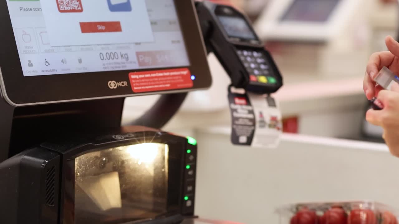 Un cliente interagisce con un'interfaccia touchscreen digitale presso una cassa self-service di un moderno supermercato