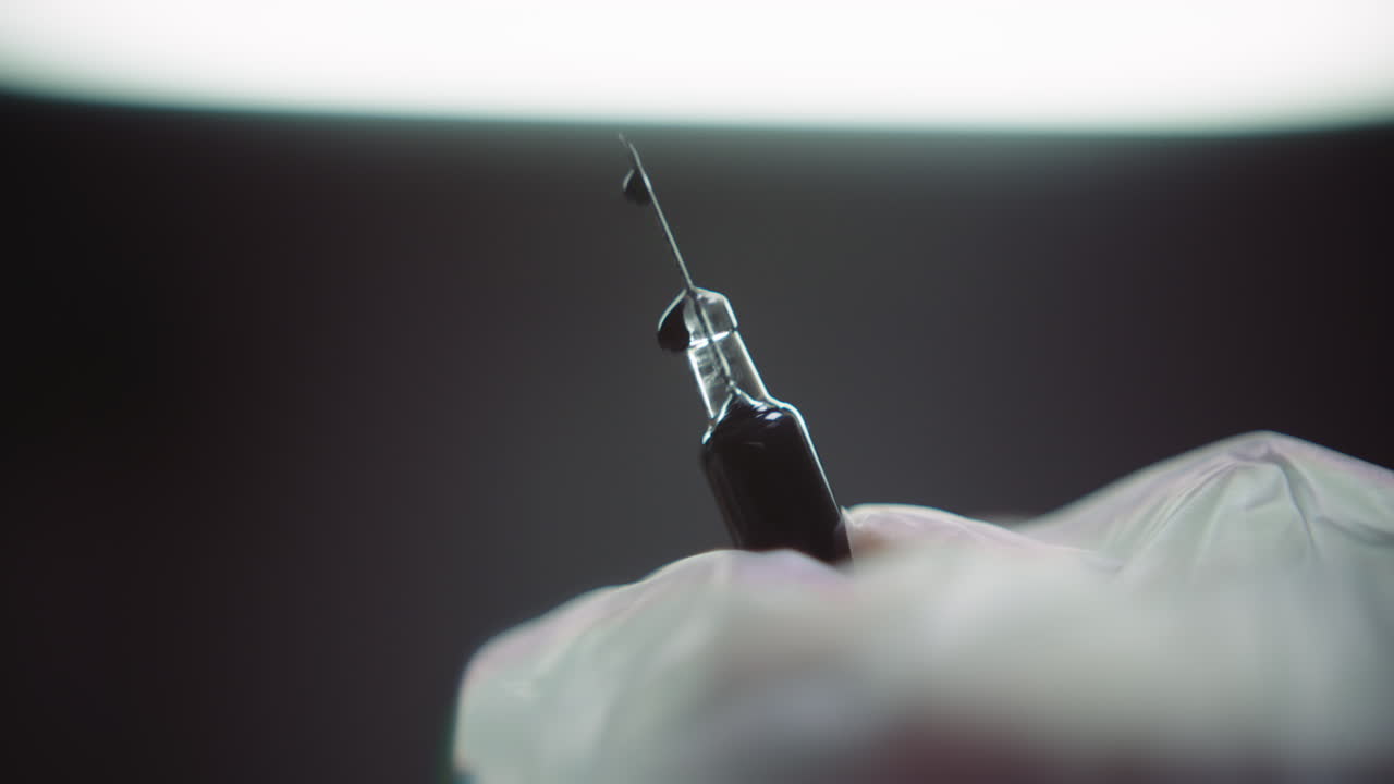 Gloved hands prepare the syringe for injection