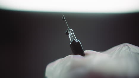 gloved hands prepare the syringe for injection