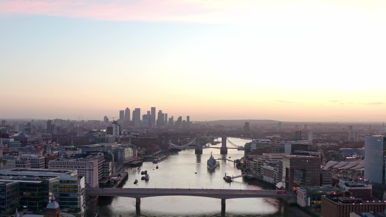 Langzame dolly-terug luchtopname met drone van de Theems, Canary Wharf en London Bridge bij zonsopgang.