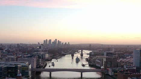 slow dolly back aerial drone shot of thames river canary wharf london bridge at sunrise