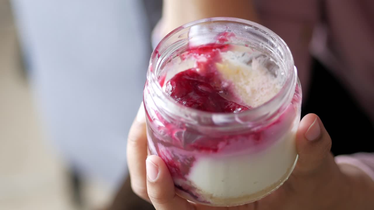 persona comiendo un frasco de pastel de queso de bayas