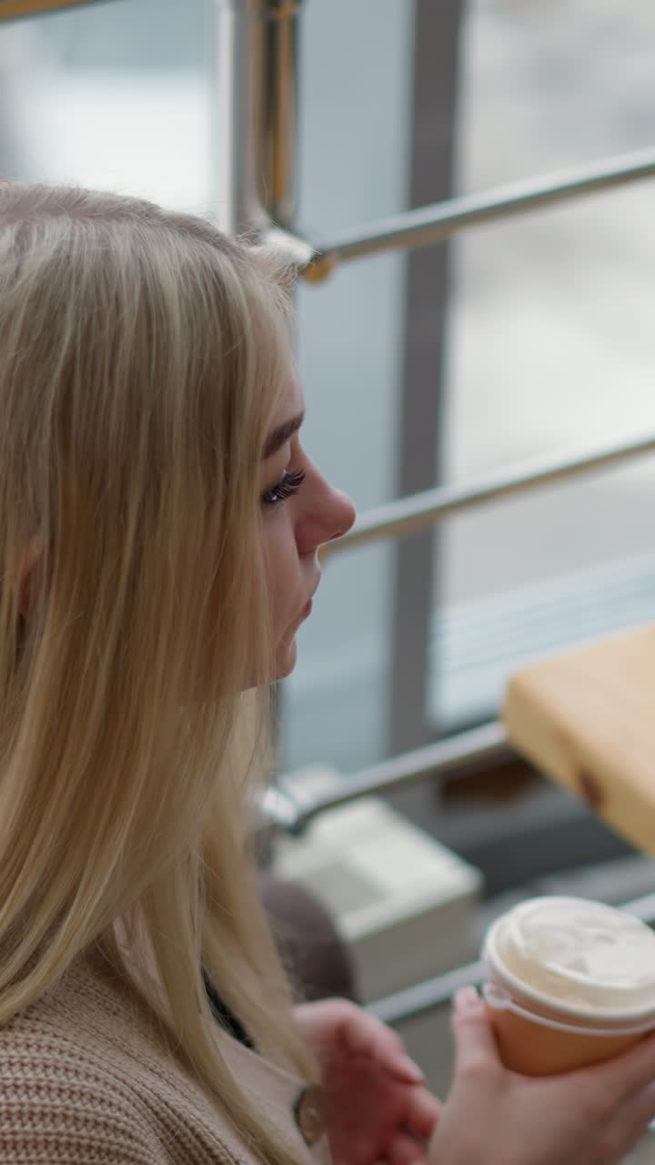 고전적인 쇼핑몰에서 술을 마시는 여자의 상공 풍경, 따뜻한 음료와 함께 아한 분위기, 쇼핑몰 건축을 특징으로하는 흐릿한 배경, 현대적인 인테리어, 평화로운 쇼핑 경험