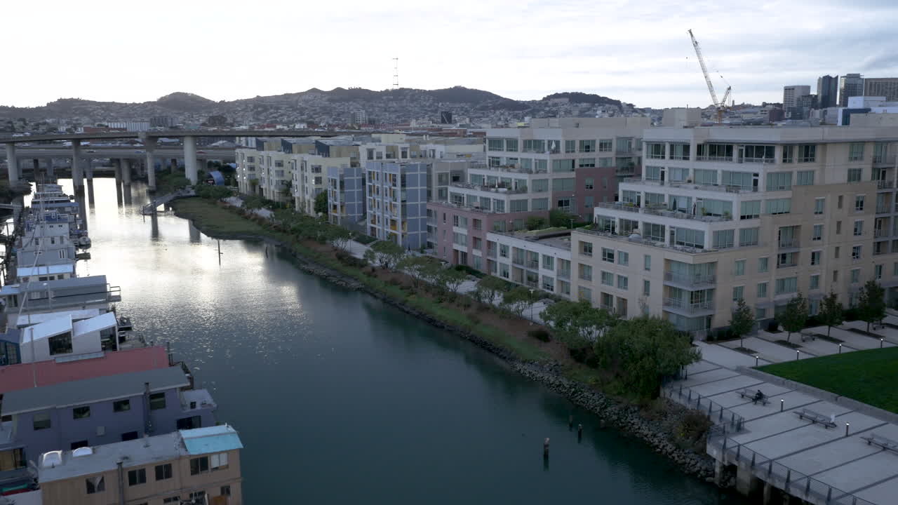 Waterfront scene with houseboats, modern apartments, and a city bridge
