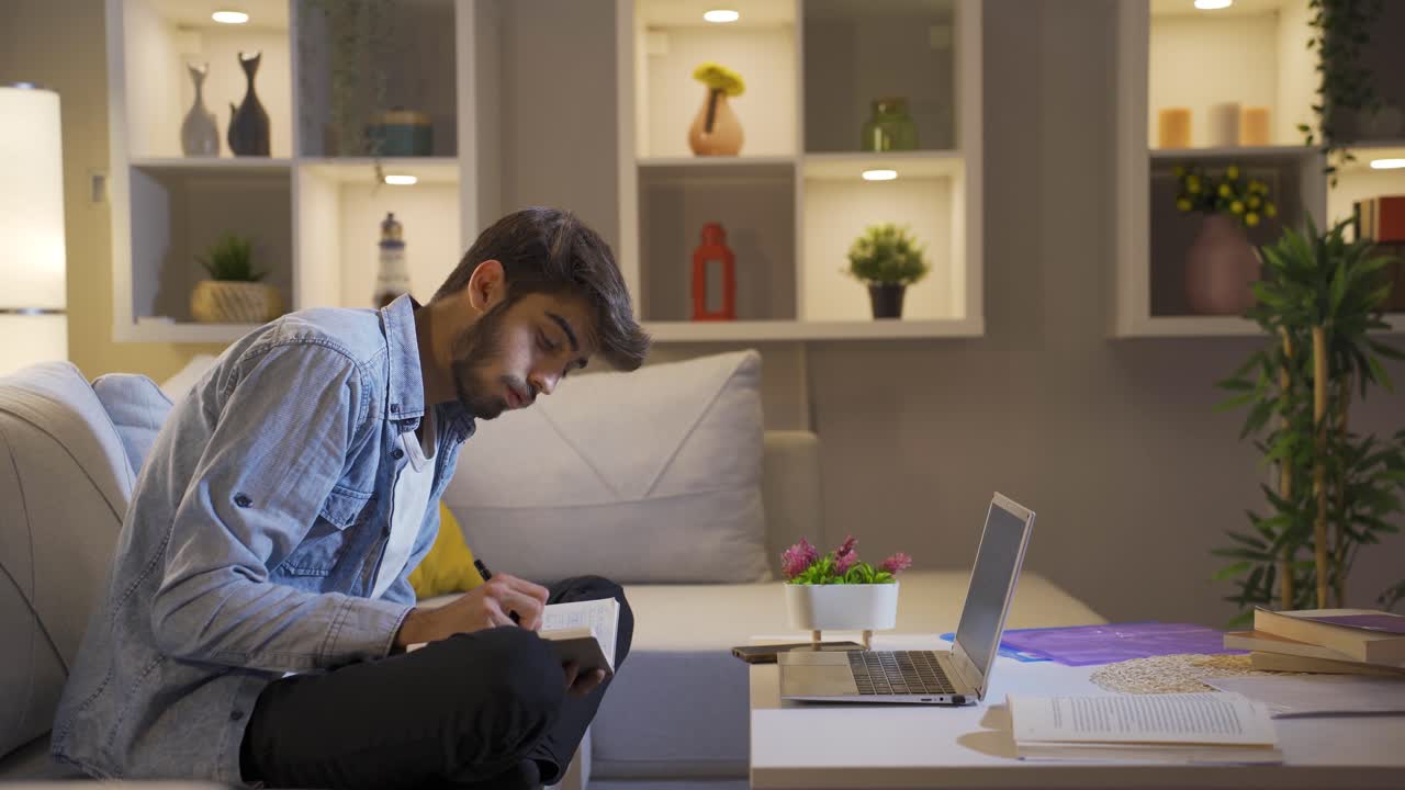 Male student studying at night in laptop light.