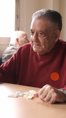 senior people playing domino game while nurse helping