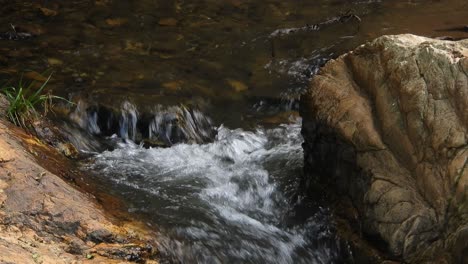 crystal clear fresh mountain waterfall crocodile river water sparkling and flowing over rocks and pebbles in the background at the walter sisulu national botanical gardens in roodepoort, south africa