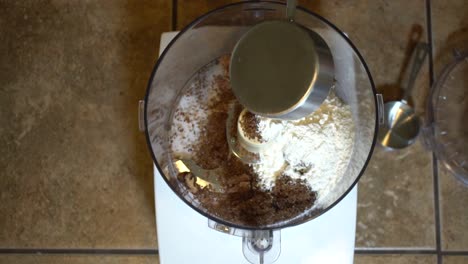 Adding-cup-of-flour-to-brown-sugar-mix-in-food-processor,-Slowmo-Overhead-View