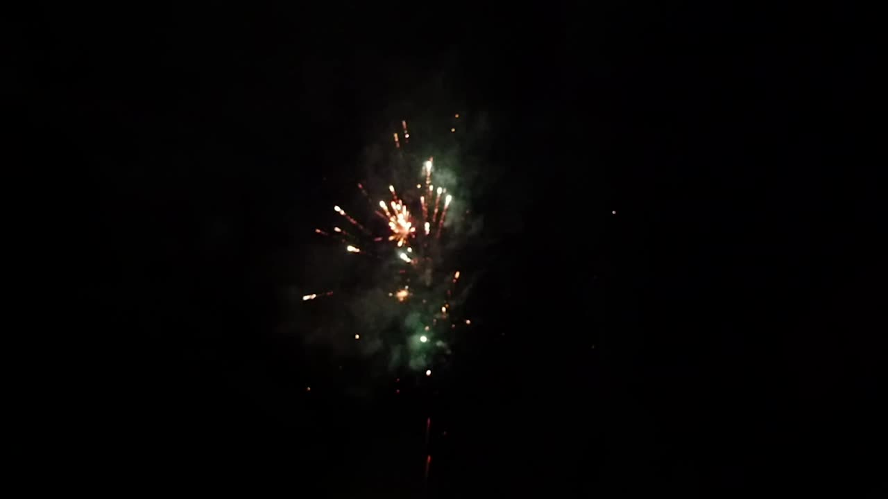 Fuochi d'artificio nel cielo notturno scuro al rallentatore con sfocatura da ripresa a mano.