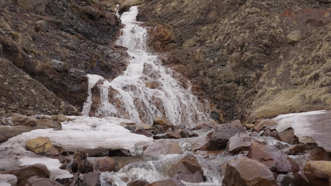 arroyo de cascada de glaciar a través del valle de la montaña volcánica naranja, islandia