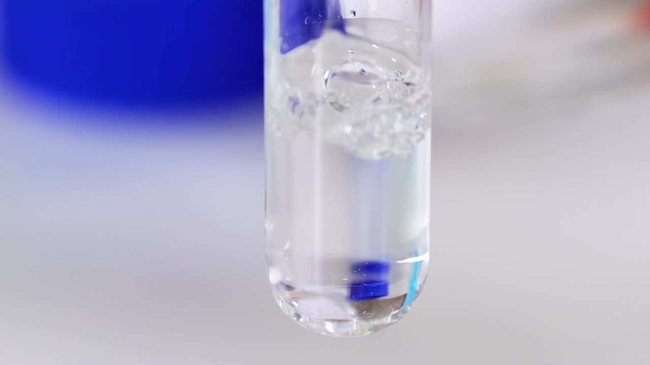 Close-up view of gas bubbles forming in a clear liquid inside a test tube.