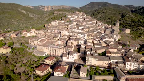 vista aérea del pequeño pueblo de penyarroya de tastavins abriéndose al valle en una soleada tarde de verano en la región de matarranya, españa