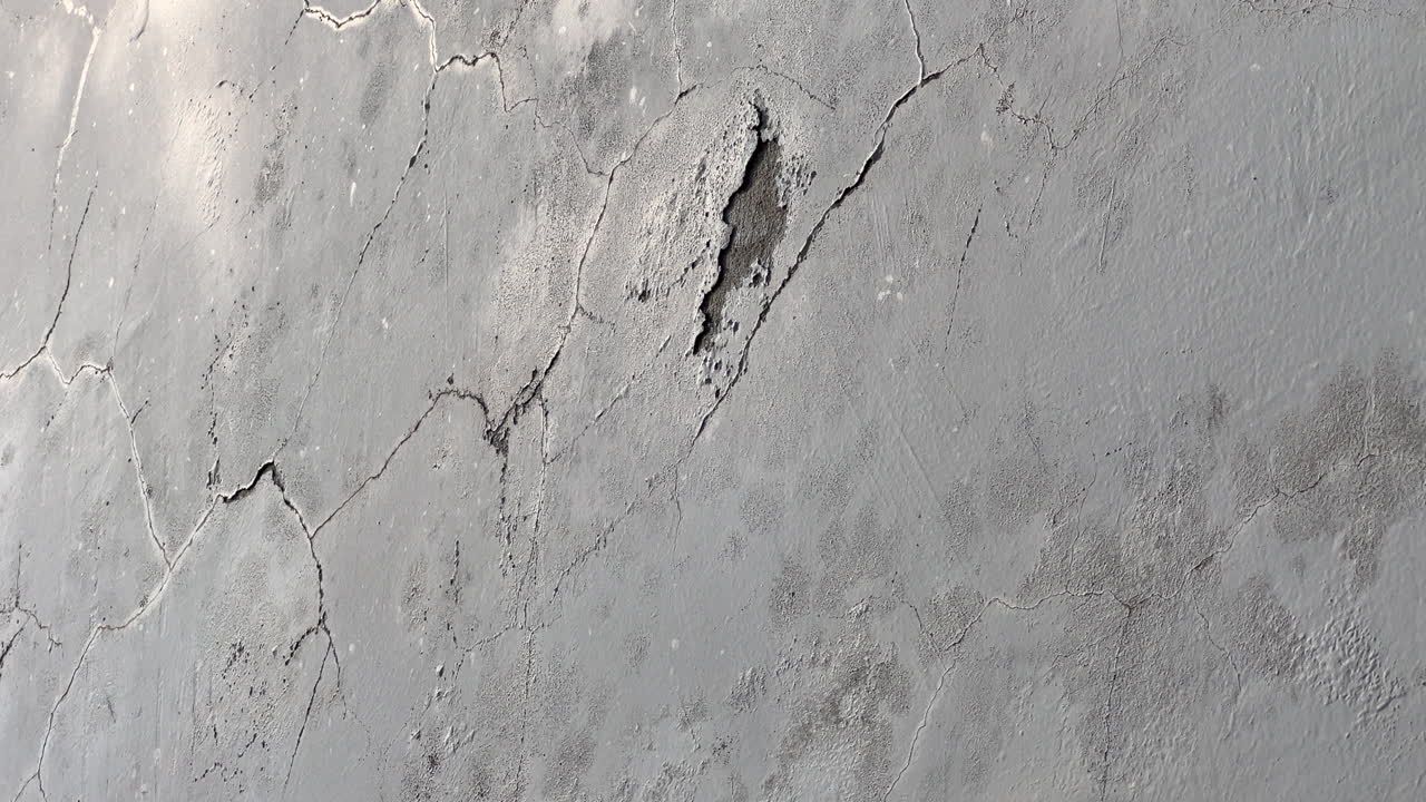 Muro intonacato di cemento invecchiato con vernice screpolata, macchie e texture ruvida, sfondo ideale per facciate grunge per concetti di ristrutturazione, degrado e manutenzione
