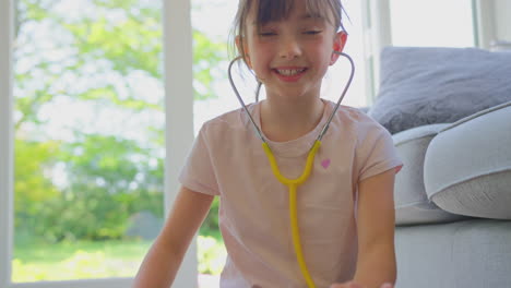 girl pretending to be veterinary surgeon at home examining pet french bulldog with stethoscope