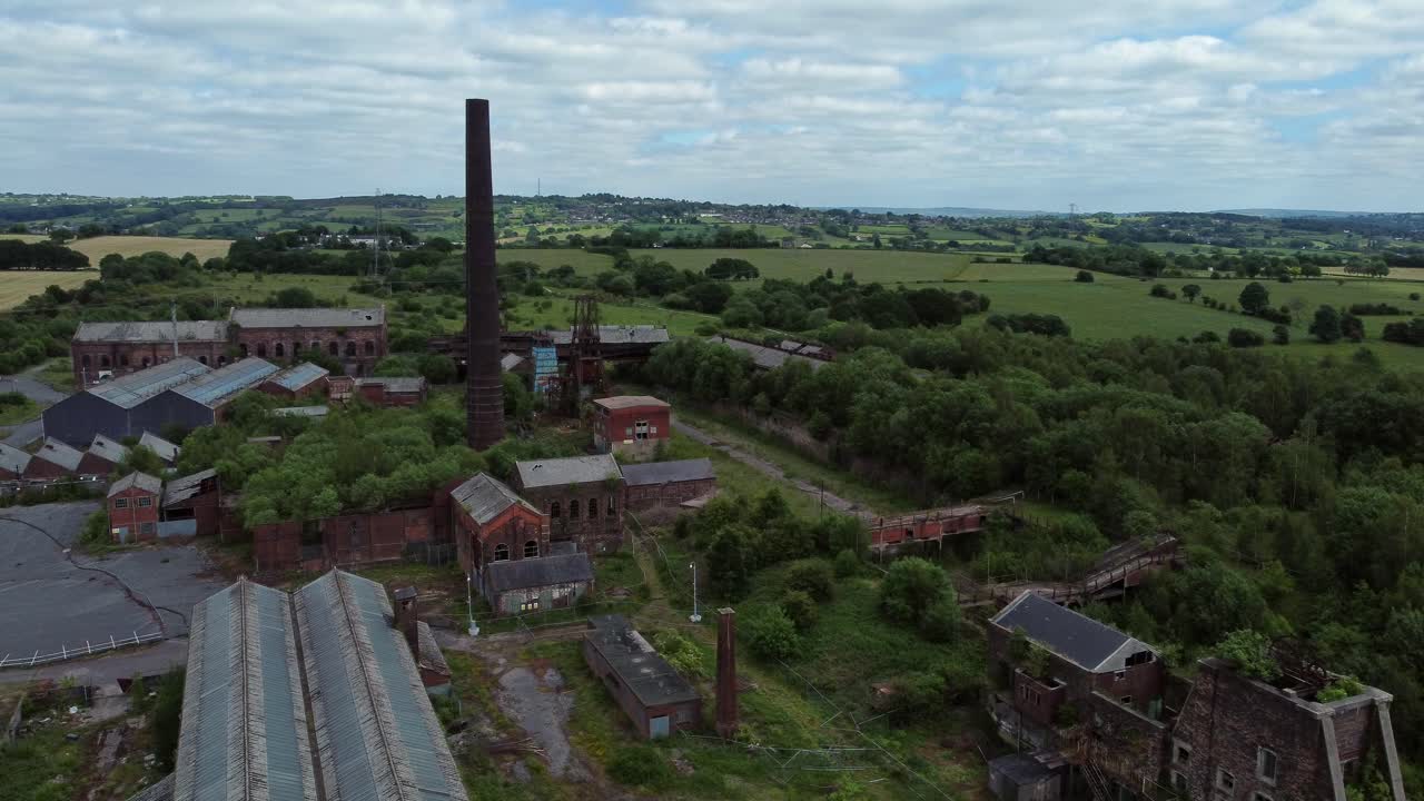 Forladte, tilgroede bygninger fra et kulmineindustrimuseum i luftperspektiv, kredser til højre.
