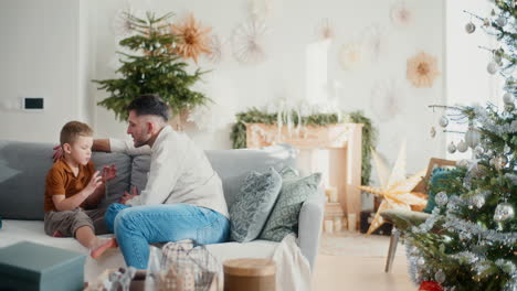 niño hablando con su padre en el sofá durante la navidad