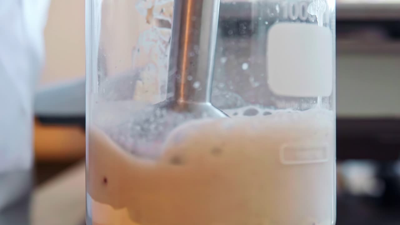 Mixer blending dough in a glass jar, kitchen scene, handheld close-up view