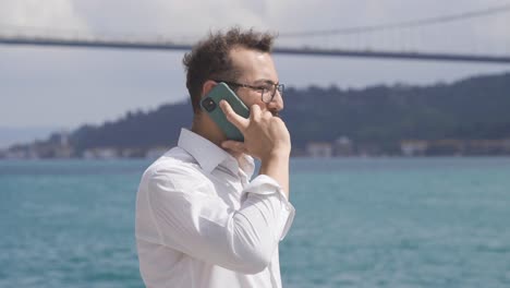 businessman talking on the phone by the sea.