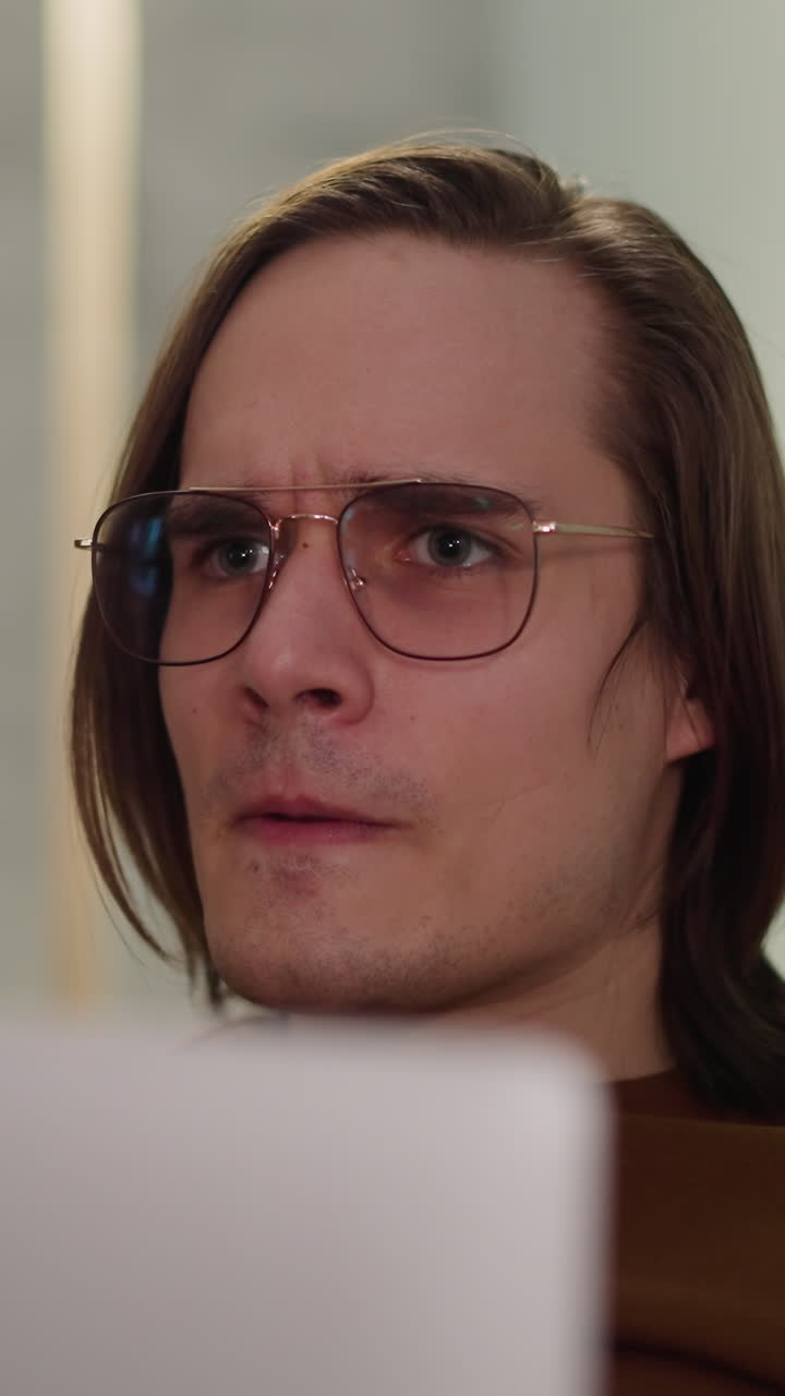 el chico de pelo largo con el portátil agarra la cabeza decepcionado por la derrota del equipo de hockey en casa en primer plano en cámara lenta.