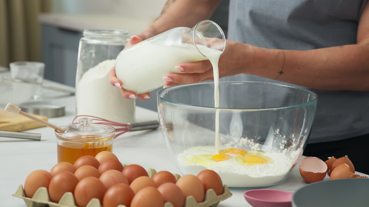 Pouring milk into a bowl with eggs to make a pastry recipe