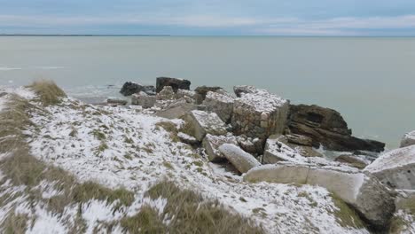 vista aérea de establecimiento de edificios de fortificación costeros abandonados en los fuertes del norte de karosta en la playa del mar báltico, día de invierno nublado, amplio tiro de drones avanzando