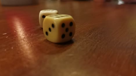 board game dice rolling across a brown wooden table