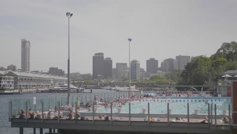 plano general de una piscina pública con mucha gente nadando durante un día soleado de verano.