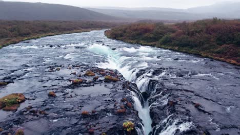 aerial: close reverse reveal of bruarfoss cascading waterfall off the golden circle in southern iceland