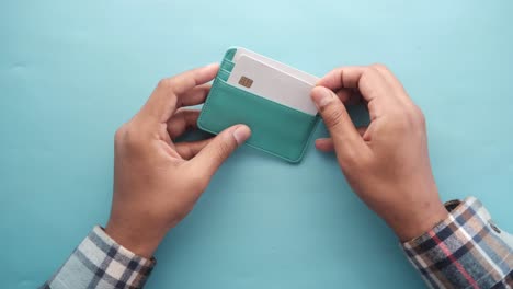 person holding a light teal leather wallet with credit cards