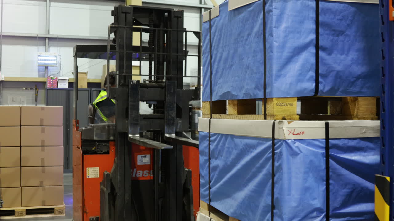 рабочий, управляющий электрическим вилочным погрузчиком внутри склада, логистическое распределение грузов, промышленный интерьер, установленная концепция рабочего класса