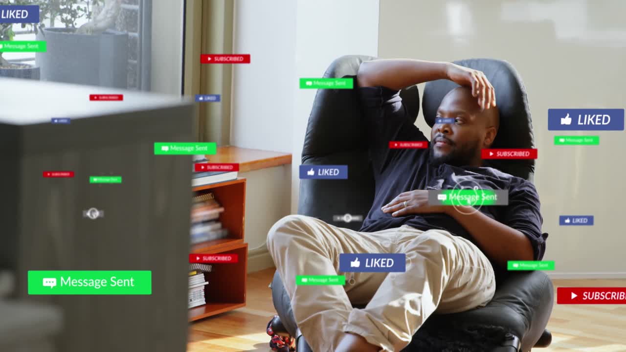 Animation of multiple social media icons over african american man looking out of window at home