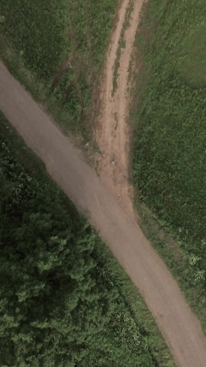 Flying over country road in green field