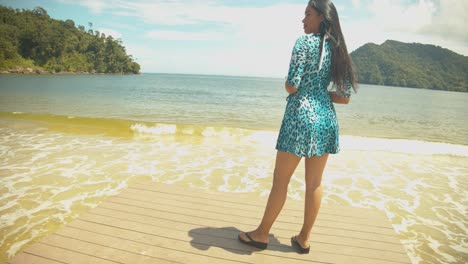 una sexy modelo venezolana posando en un embarcadero con montañas y una playa al fondo