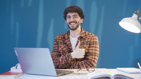 Feliz-Estudiante-Varón-Estudiando-En-El-Escritorio-Y-Mirando-A-La-Cámara-Sonriendo-Y-Expresando-Feliz-Estudio.