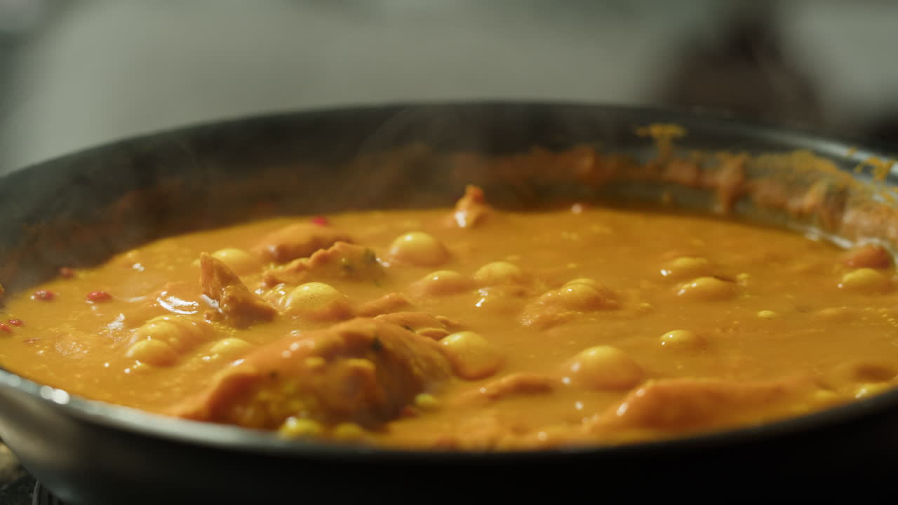Yellow boiling sauce on pan close-up. Asian cuisine concept. Curry is a dish with a sauce seasoned with spices. Curries may contain fish, meat, poultry, or shellfish, either alone or in combination with vegetables. Others are vegetarian.