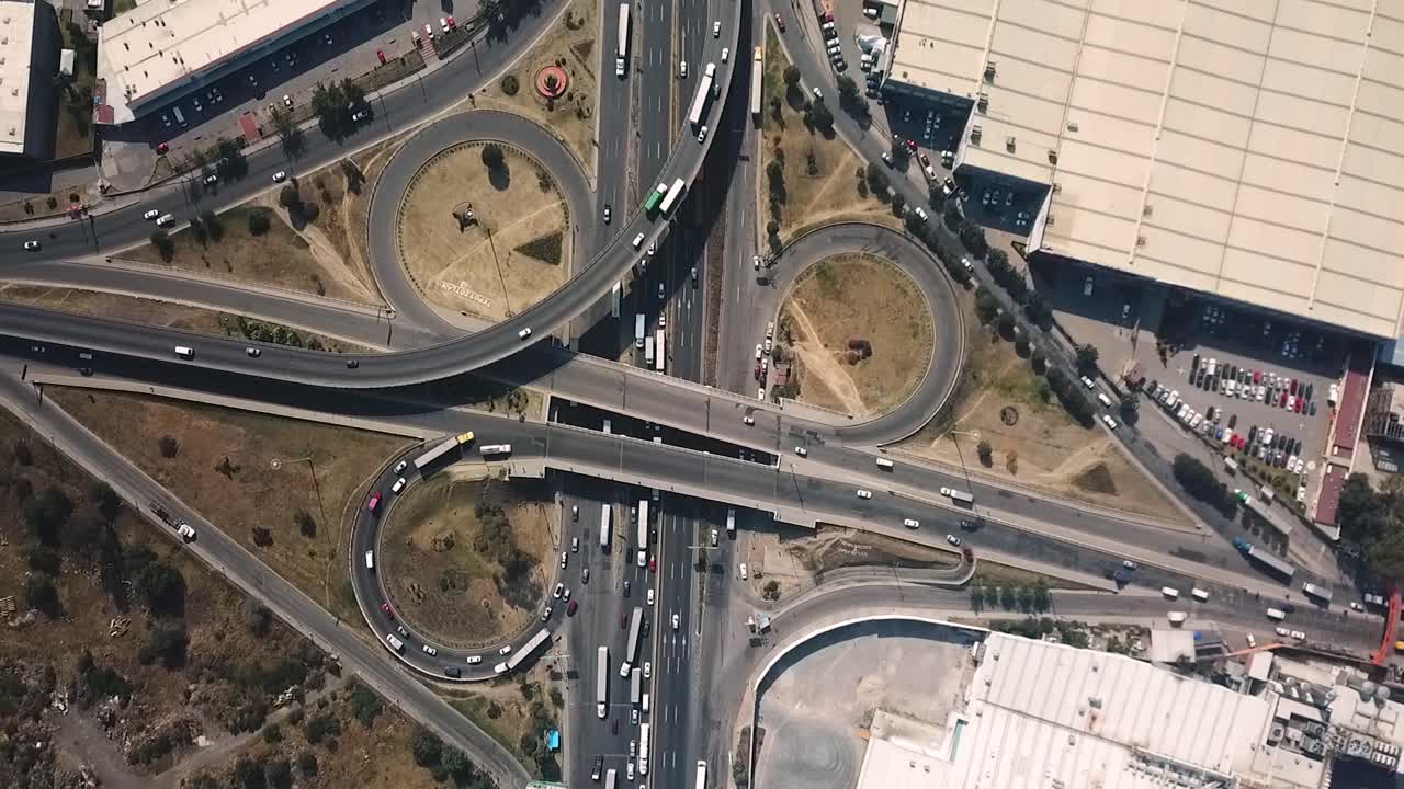 Drone shot pulling away from the road infrastructure on the Mexico-Querétaro highway, featuring the interchange in the Tepotzotlán area, before exiting the metropolitan zone of Mexico City