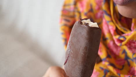 woman eating a chocolate covered ice cream popsicle