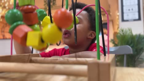 very expressive and happy three-year-old black child playing with a colorful toy in a cafeteria